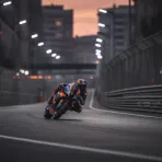 A MotoGP bike navigates a floodlit city street circuit at speed, representing the new Adelaide Grand Prix.