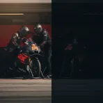 The two Aprilia Racing MotoGP bikes side-by-side in the pit garage, each with its own crew of mechanics.