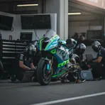 A Yamaha MotoGP bike in the pit garage at Silverstone, with engineers analysing data on laptops around it.
