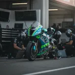 A Yamaha MotoGP bike in the pit garage at Silverstone, with engineers analysing data on laptops around it.