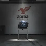 A lone racing helmet rests on a stool in an otherwise empty and quiet MotoGP pit garage, signifying a rider's absence due to injury.