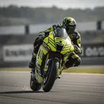 A rider on a yellow and black MotoGP race bike brakes heavily into a corner during a race.