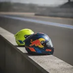 A fluorescent yellow helmet and a dark blue and orange helmet sit together on a pit wall, symbolising the rider moves between the VR46 and KTM teams.
