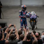 A MotoGP rider presents a signed helmet for auction at the GP of Champions charity event at Silverstone.