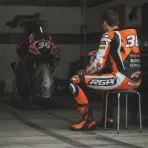 A factory Honda rider sits in his garage looking concerned after a difficult race.