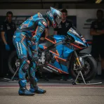 A MotoGP rider prepares in his pit garage, focusing on his fitness before heading out onto the track.