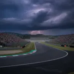Johann Zarco's empty pit box at a MotoGP circuit, with his chair and computer monitors under a spotlight.