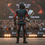 A former motorcycle racer holds his MotoGP Legend medallion on stage during an awards ceremony.