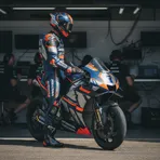 A rider in factory Honda colours stands beside his bike in the pit box, reflecting on the session.