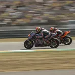 A MotoGP rider chases a rival at high speed during the German Grand Prix, symbolising a close championship battle.