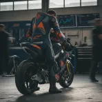 A MotoGP rider contemplates his helmet and bike in the pit garage before a session.