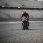 A MotoGP rider looks downcast after being forced to retire his bike at the side of the Aragon circuit.