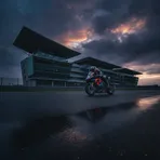 The famous Silverstone Wing building overlooks the empty race circuit under a dramatic, cloudy sky ahead of the British Grand Prix.