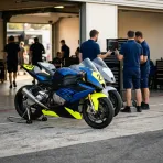 Illustration for our team orders story: two racing motorcycles standing inside a brightly lit pit garage beside mechanics.